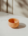 Minimalistische henkellose Tasse in Korallfarbe, Teil des TANO Cappuccino 2er-Sets. Zeitloses nordisches Design auf deutsch.